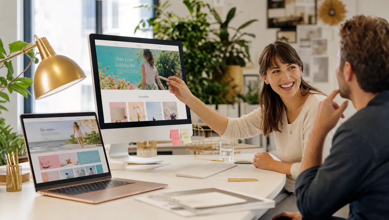 KI-generiertes Bild: zwei Menschen im hellen Büro besprechen bunte Website-Entwürfe am Bildschirm